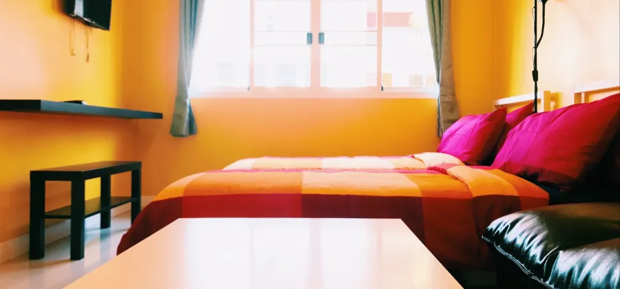ห้องมาตรฐาน เตียงควีนไซส์ ผนังสีเหลือง มีหน้าต่างรับแสงธรรมชาติ